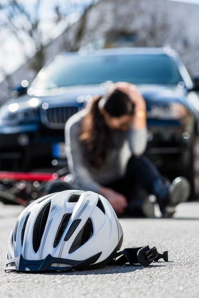 Bicycle helmet lying on the asphalt after a collision between a woman's bike and a 4x4 car in the city.