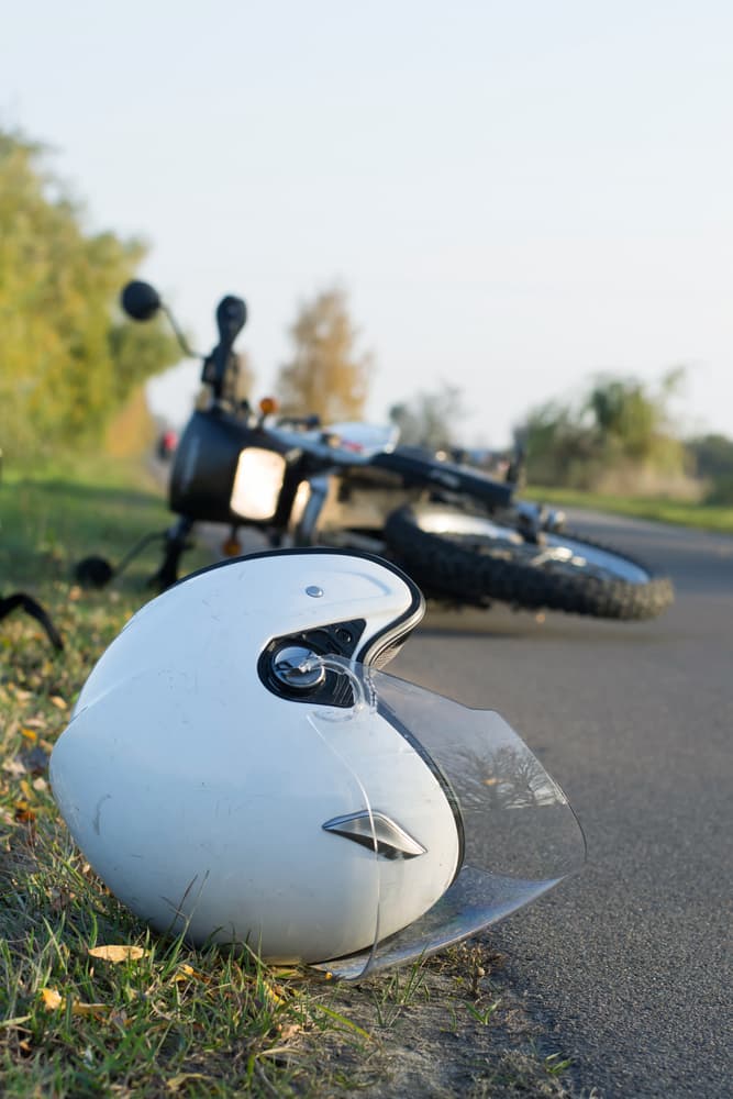 Helmet and motorcycle lying on the road, illustrating the concept of road accidents.