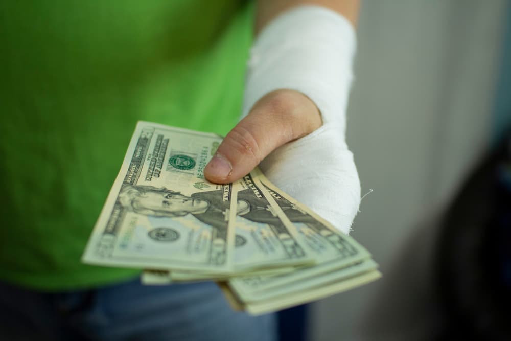A man with a cast on his arm counting money for medical expenses at the hospital.