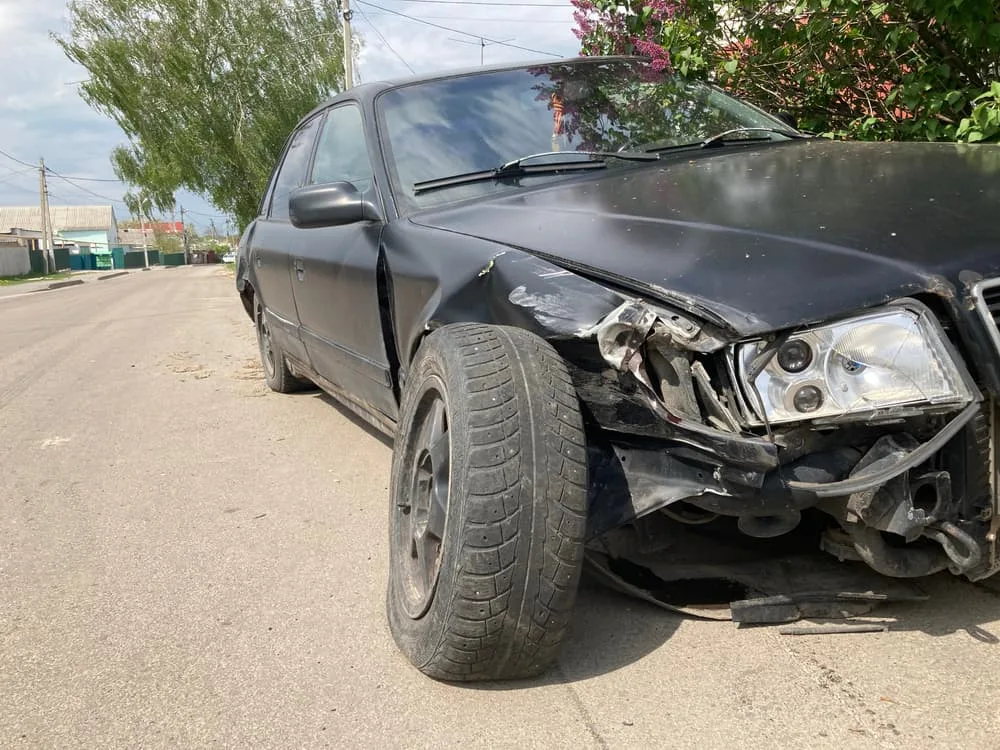 "The car body is heavily damaged from a high-speed head-on traffic collision, resulting in dents on the highway.