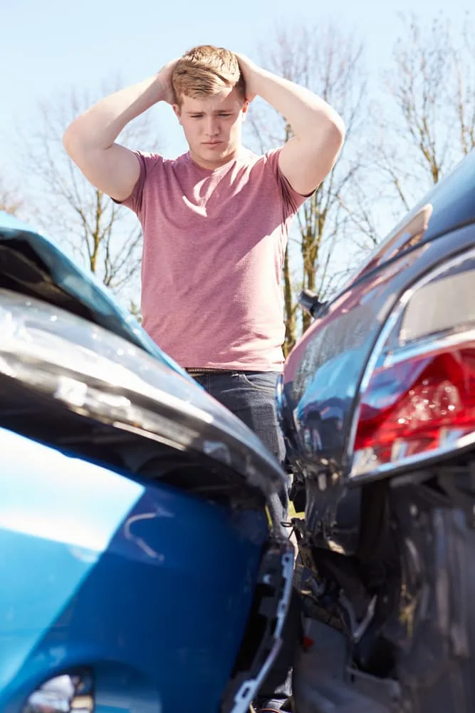 Upset driver standing near damaged vehicle after a traffic accident in Tysons Corner, VA.