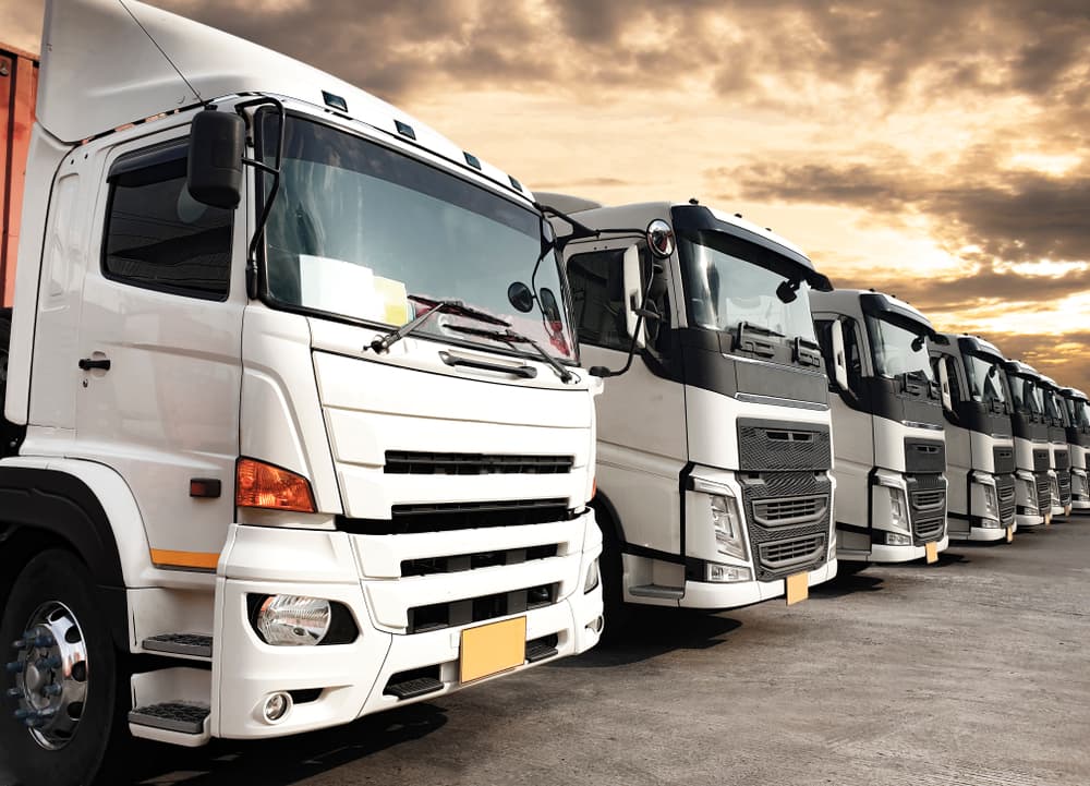 Trucks lined up at sunset, symbolizing the road freight industry's cargo service and the logistics and transport sector.