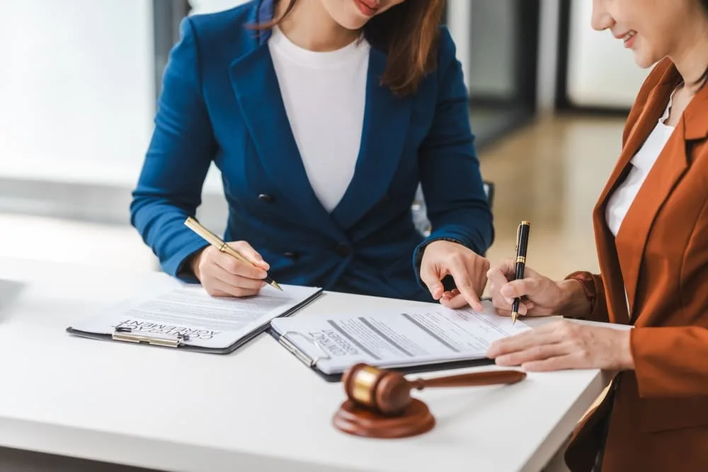 A female lawyer and her client discuss a legal contract, concentrating on legislation and women's rights, in a law office.