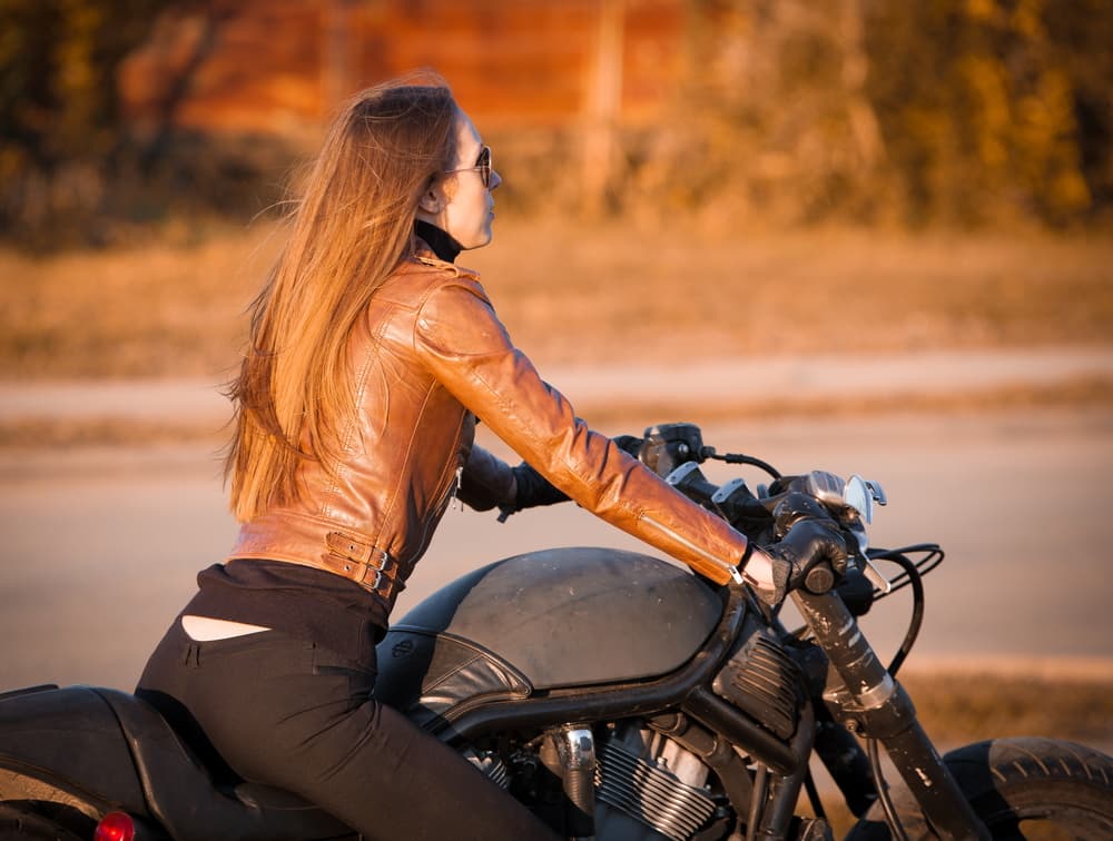 A beautiful woman with elegant dark hair, dressed in a brown leather jacket, exudes a sense of joy and fun.