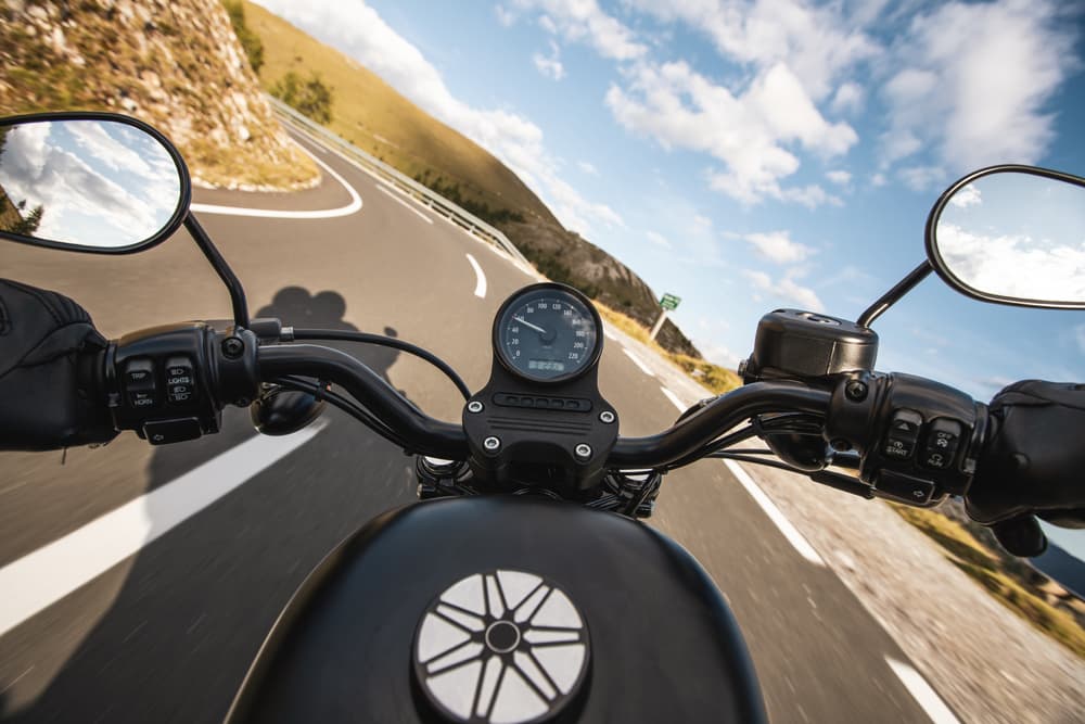 A motorcyclist navigating a sharp turn on an asphalt road in the mountains