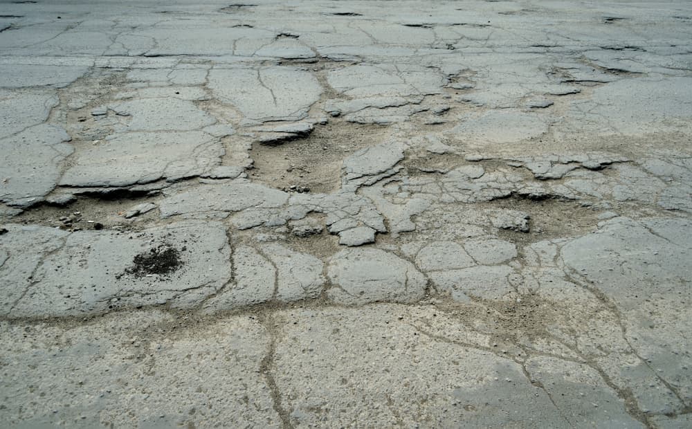 View from above of damaged road with pits and scattered stones on the asphalt, showing poor road conditions in need of repair. Concept of road construction and maintenance.