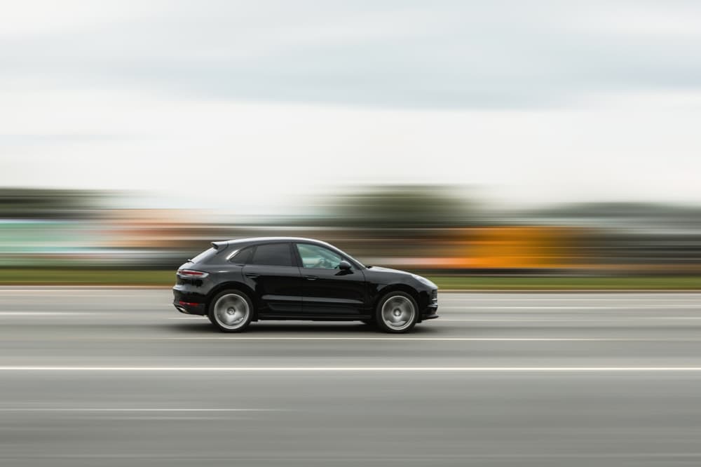 A black car speeding down the street with a blurred background, illustrating the concept of speeding, disobeying traffic rules, and dangerous driving.