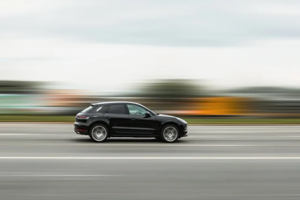 A black car speeding down the street with a blurred background, illustrating the concept of speeding, disobeying traffic rules, and dangerous driving.