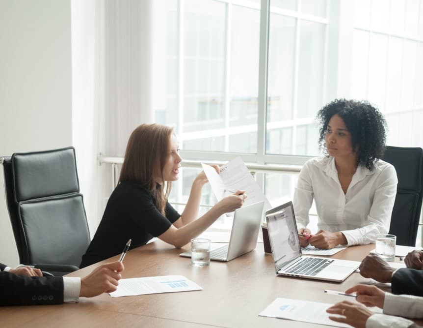 Deceived and dissatisfied businesswoman arguing about bad business contract terms during a meeting with diverse lawyers and partners, demanding compensation in a legal dispute.