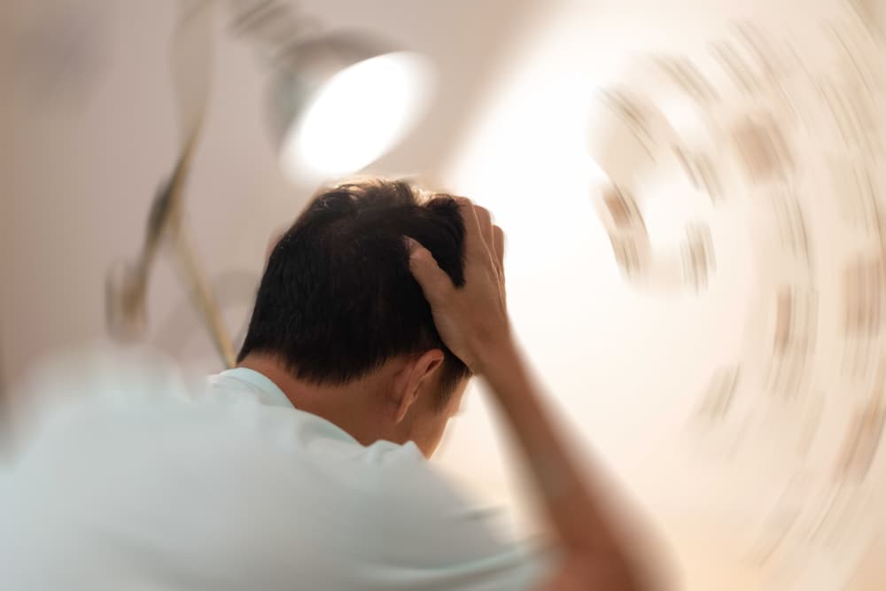 Man hands on his head felling headache dizzy sense of spinning dizziness,a problem with the inner ear, brain, or sensory nerve pathway.