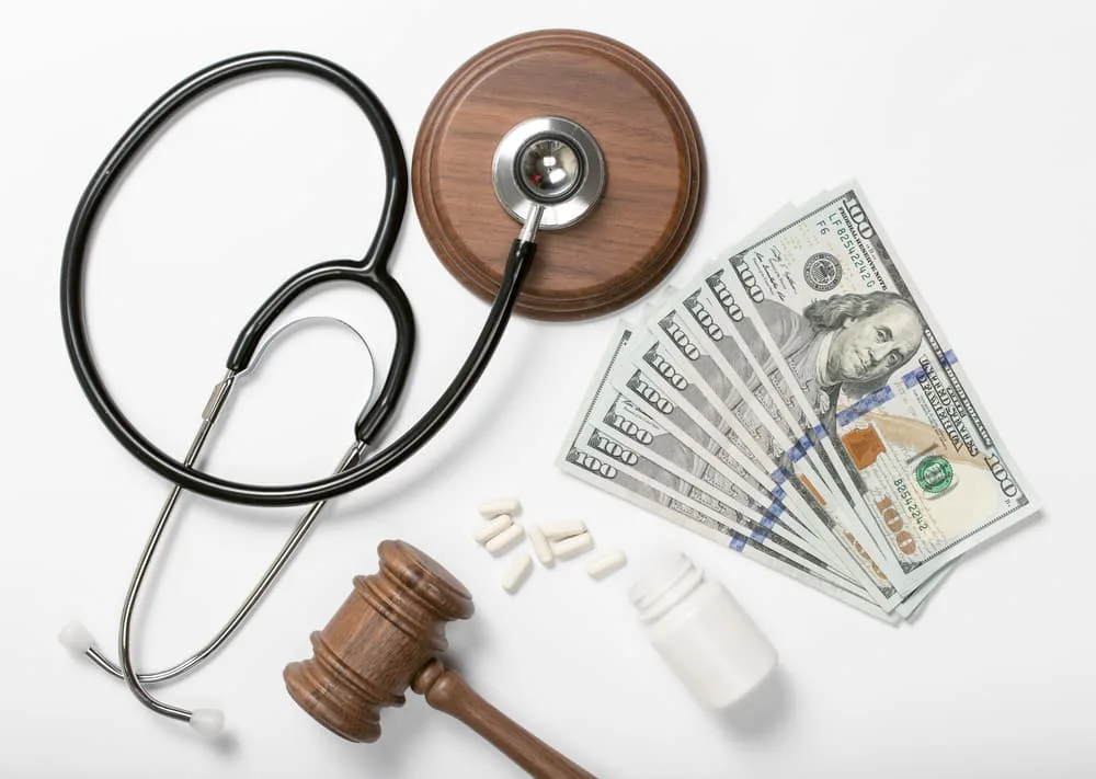 Medical stethoscope, pills, judge hammer and money on a white background