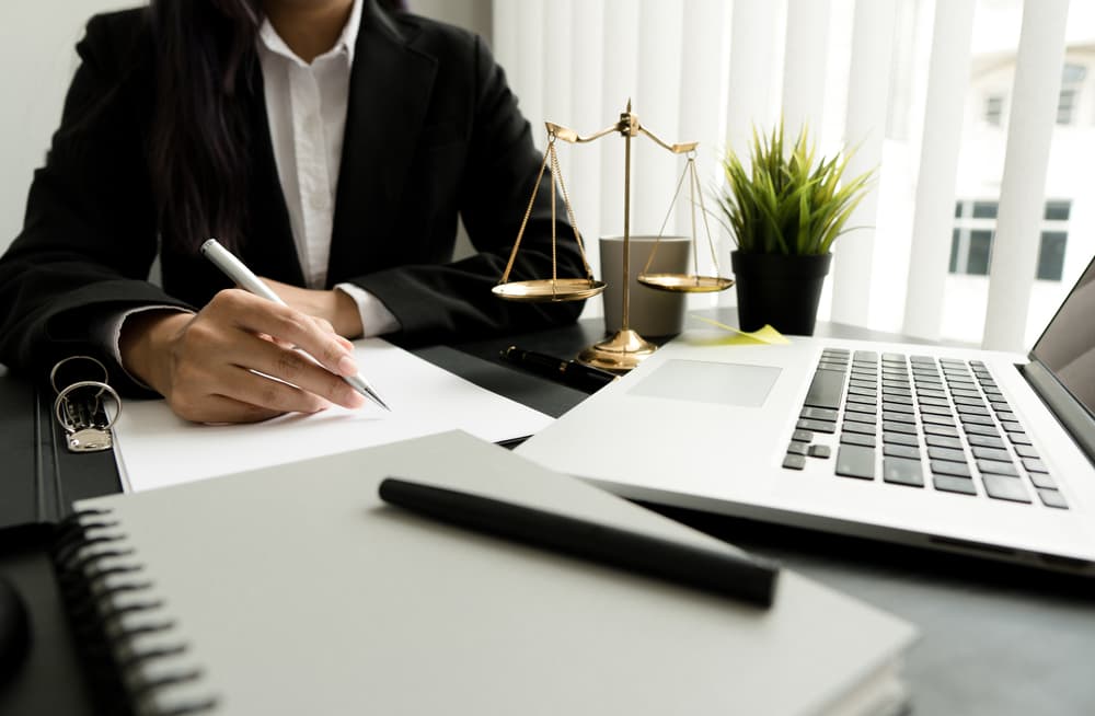 Female lawyer working with contract papers and wooden gavel on table in courtroom.
