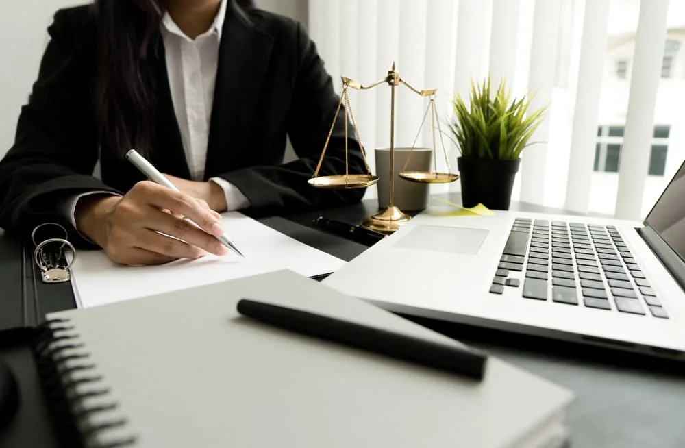Female lawyer working with contract papers and wooden gavel on table in courtroom.