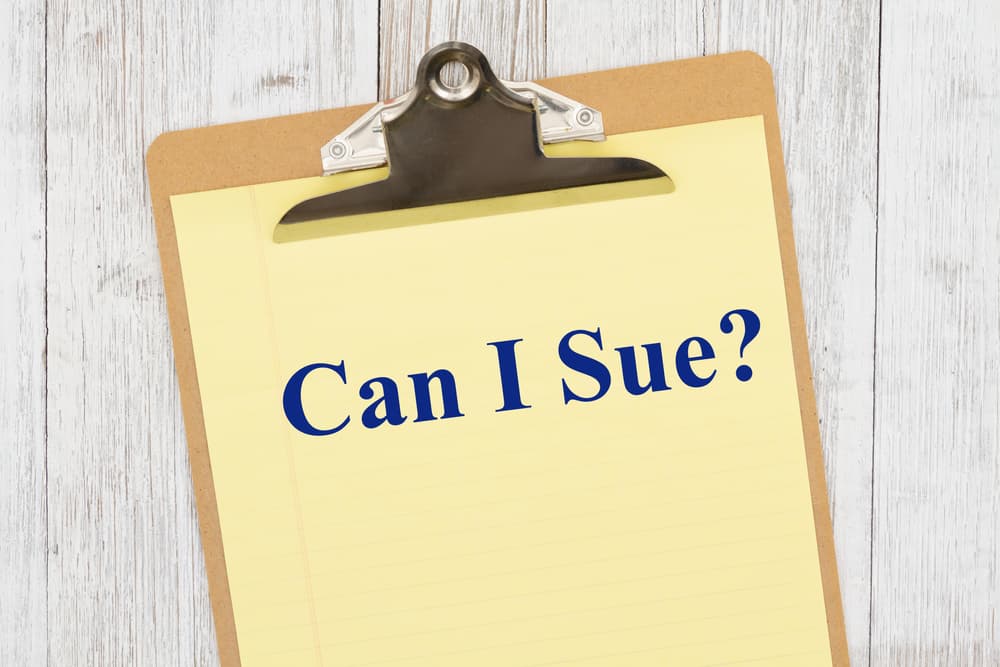 Can I sue question on yellow legal paper on a clipboard on weathered whitewash wood