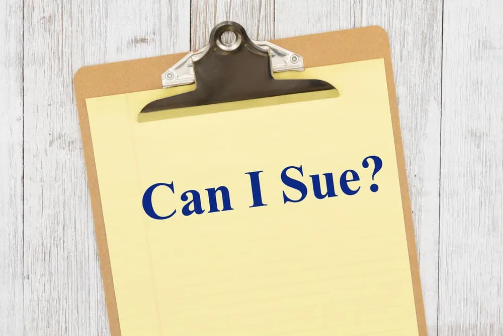 Can I sue question on yellow legal paper on a clipboard on weathered whitewash wood