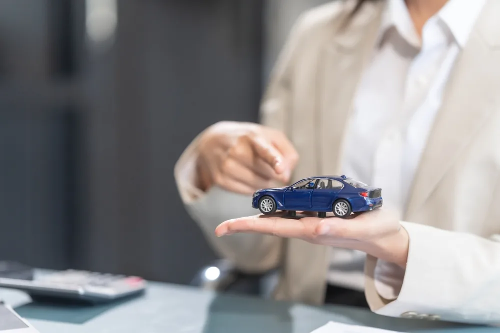 A female car accident lawyer holding car model in hand