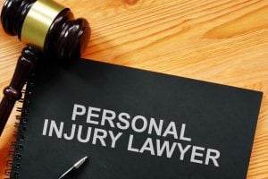 A gavel, a pen, and a black folder labeled "Personal Injury Lawyer" on a wooden desk.
