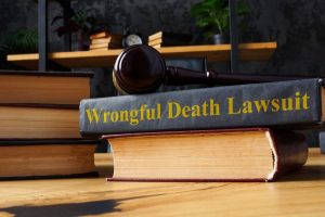 A gavel rests on a stack of law books, with one prominently titled "Wrongful Death Lawsuit" on a wooden desk.