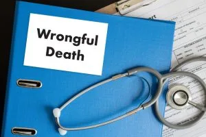 A blue binder labeled "Wrongful Death" next to a stethoscope and paperwork on a desk.