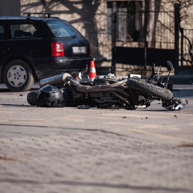 Accident with motorcycle at a crossroads. A motorcyclist's helmet lies next to a broken bike.